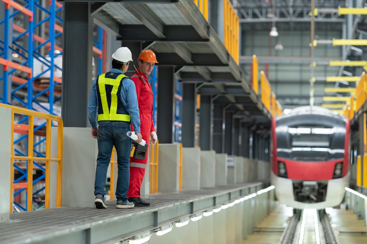 Zwei Mitarbeiter in Arbeitskleidung im Betriebswerk vor einem Elektrotriebzug